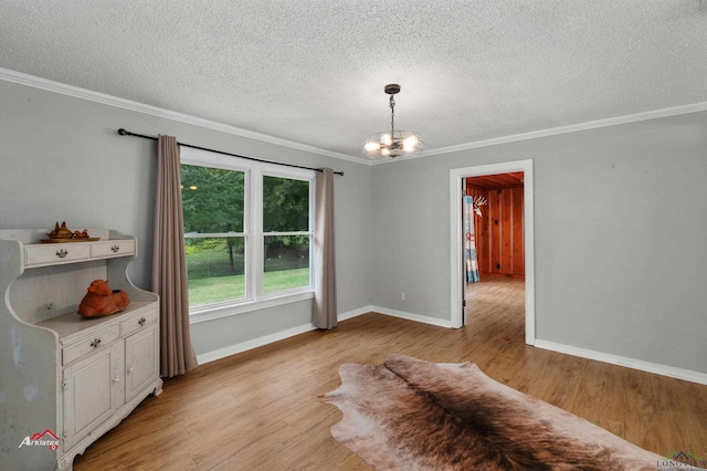 unfurnished dining area featuring a textured ceiling, a notable chandelier, light wood-type flooring, and ornamental molding