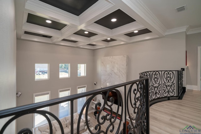 corridor featuring beam ceiling, light wood-type flooring, crown molding, and coffered ceiling