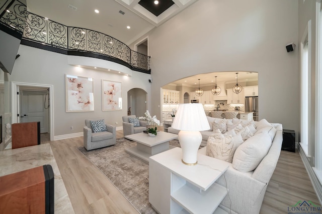 living room with a towering ceiling and light hardwood / wood-style flooring