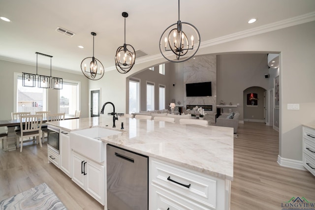 kitchen with decorative light fixtures, dishwasher, a center island with sink, sink, and an inviting chandelier