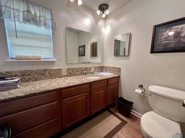 bathroom featuring toilet, wood-type flooring, vanity, and a textured ceiling