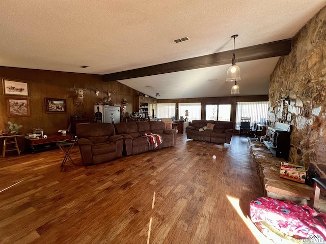 living room featuring wooden walls, a textured ceiling, lofted ceiling with beams, and dark wood-type flooring