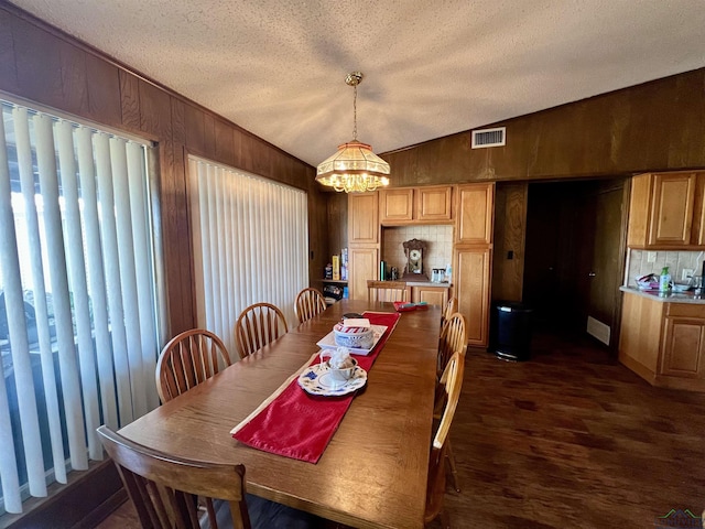 dining space featuring a textured ceiling, dark hardwood / wood-style flooring, vaulted ceiling, and a chandelier