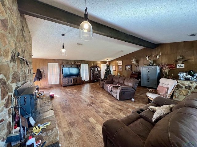 living room with a textured ceiling, wooden walls, lofted ceiling with beams, and hardwood / wood-style floors