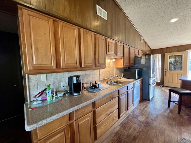 kitchen with dark wood-type flooring, a textured ceiling, light stone countertops, lofted ceiling, and sink