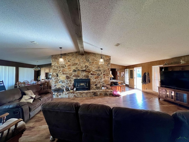 living room featuring a textured ceiling, lofted ceiling with beams, wood walls, a wood stove, and wood-type flooring