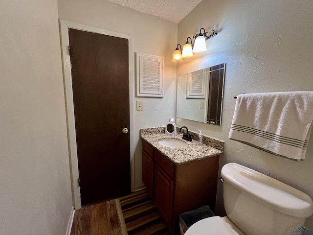 bathroom featuring toilet, a textured ceiling, vanity, and hardwood / wood-style floors