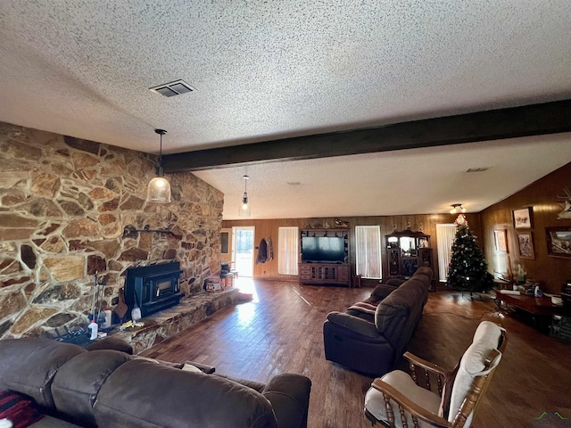 living room with wooden walls, a textured ceiling, a wood stove, hardwood / wood-style floors, and lofted ceiling with beams