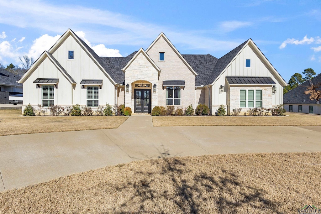 modern inspired farmhouse featuring a front lawn and french doors