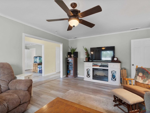 living room featuring ceiling fan, ornamental molding, and light hardwood / wood-style flooring