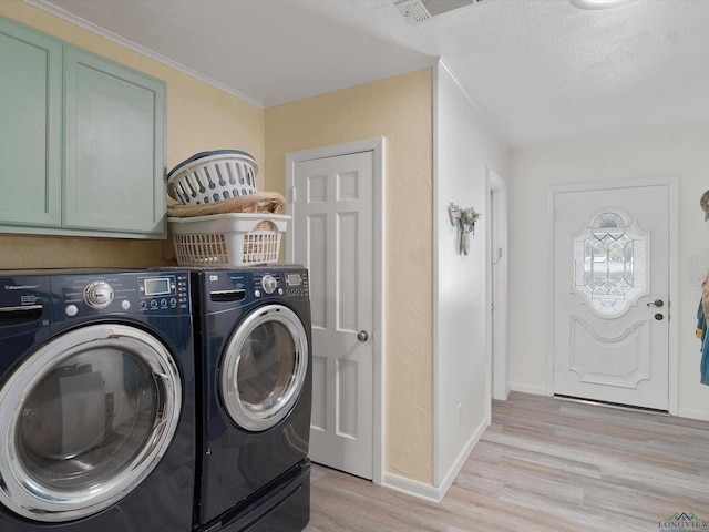 clothes washing area featuring a textured ceiling, cabinets, separate washer and dryer, and light wood-type flooring