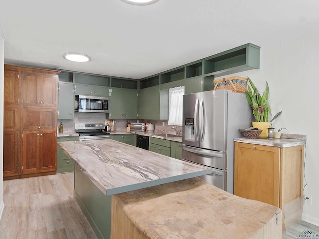 kitchen with a center island, green cabinets, backsplash, light hardwood / wood-style floors, and appliances with stainless steel finishes