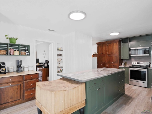 kitchen featuring green cabinets, light hardwood / wood-style flooring, appliances with stainless steel finishes, a kitchen island, and ornamental molding