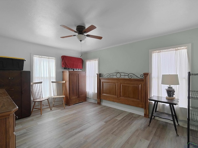 bedroom featuring ceiling fan, light wood-type flooring, and crown molding