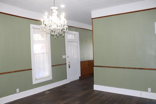 empty room with dark hardwood / wood-style flooring and a chandelier