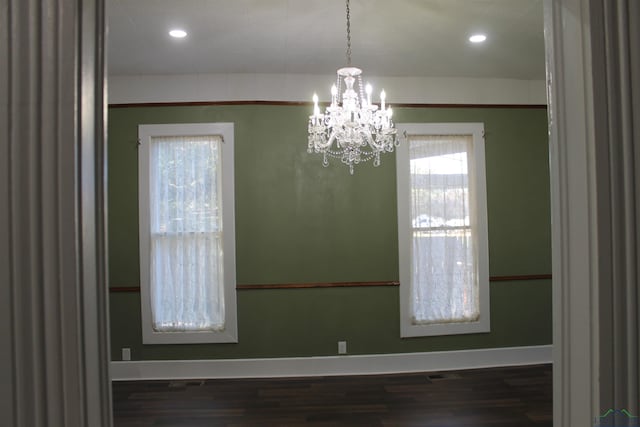 unfurnished dining area with dark hardwood / wood-style flooring and an inviting chandelier