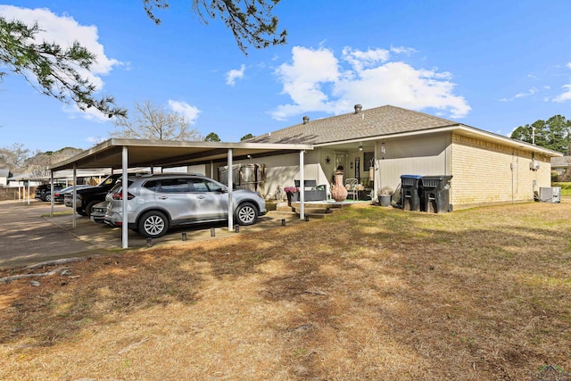 back of property with brick siding, central AC, and a lawn