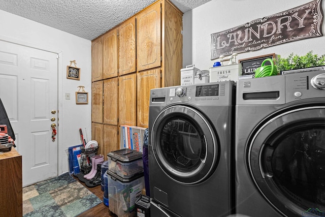 clothes washing area featuring cabinet space, a textured ceiling, wood finished floors, and washing machine and clothes dryer