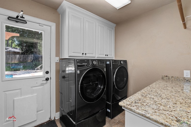 laundry area with washer and clothes dryer, light tile patterned floors, and cabinets