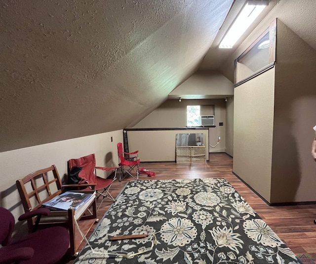 additional living space featuring hardwood / wood-style floors, a wall mounted air conditioner, lofted ceiling, and a textured ceiling