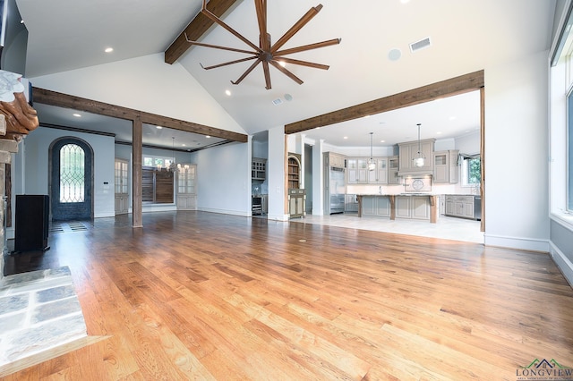 unfurnished living room with high vaulted ceiling, beam ceiling, light hardwood / wood-style floors, and a wealth of natural light