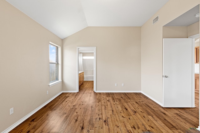 unfurnished bedroom featuring light hardwood / wood-style floors and lofted ceiling