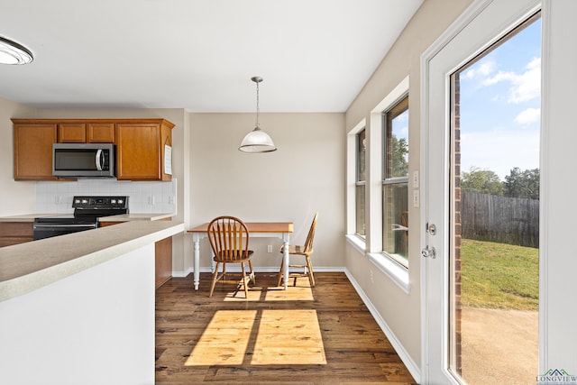 kitchen with decorative backsplash, electric range, dark wood-type flooring, and hanging light fixtures