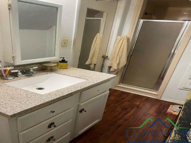 bathroom with vanity, hardwood / wood-style flooring, and a shower with shower door