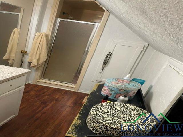 bathroom with vanity, a textured ceiling, wood-type flooring, lofted ceiling, and a shower with shower door