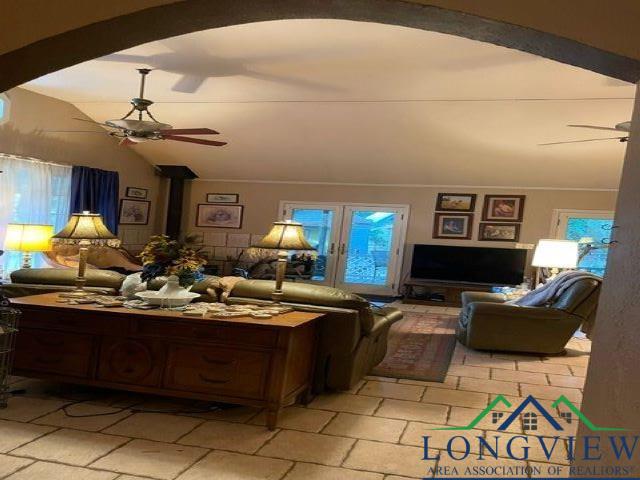 living room featuring a wood stove, ceiling fan, lofted ceiling, and ornamental molding