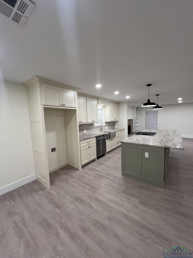 kitchen with dishwashing machine, wood finished floors, a kitchen island, visible vents, and white cabinetry