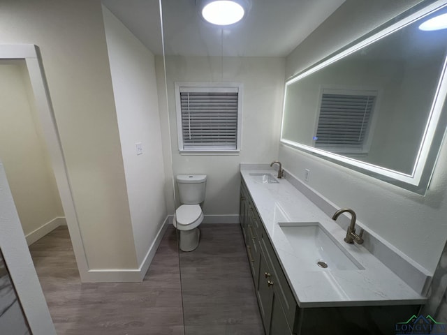 full bathroom with baseboards, a sink, toilet, and double vanity