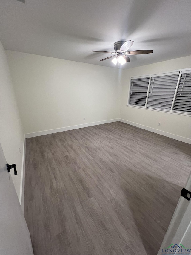 empty room with dark wood-style flooring, ceiling fan, and baseboards