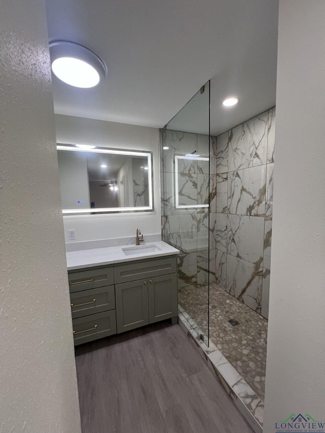 full bath featuring wood finished floors, a marble finish shower, and vanity