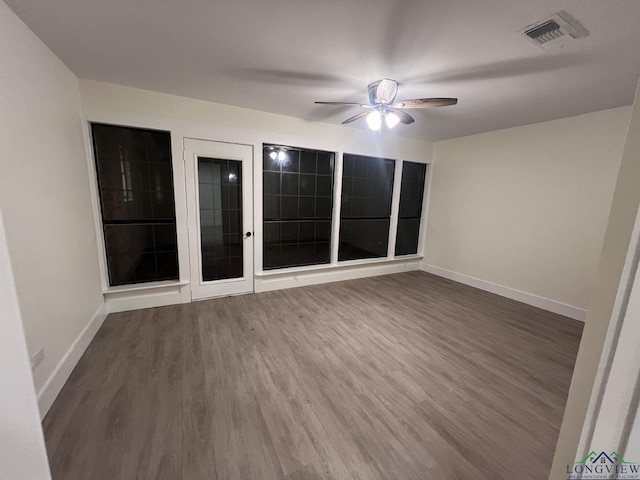 empty room with visible vents, ceiling fan, baseboards, and wood finished floors