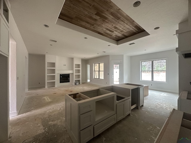 kitchen featuring a tray ceiling, built in shelves, a center island, and gray cabinetry