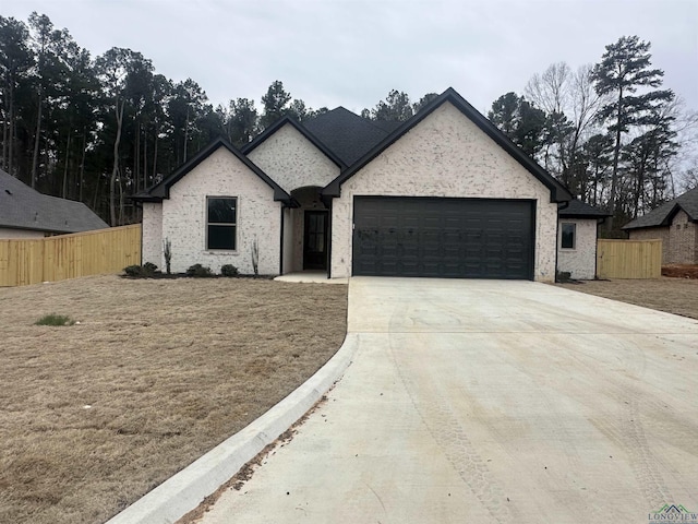 view of front of property with a garage, brick siding, fence, and driveway