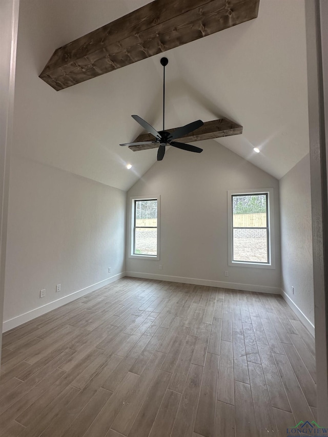 empty room with a ceiling fan, lofted ceiling, baseboards, and light wood finished floors