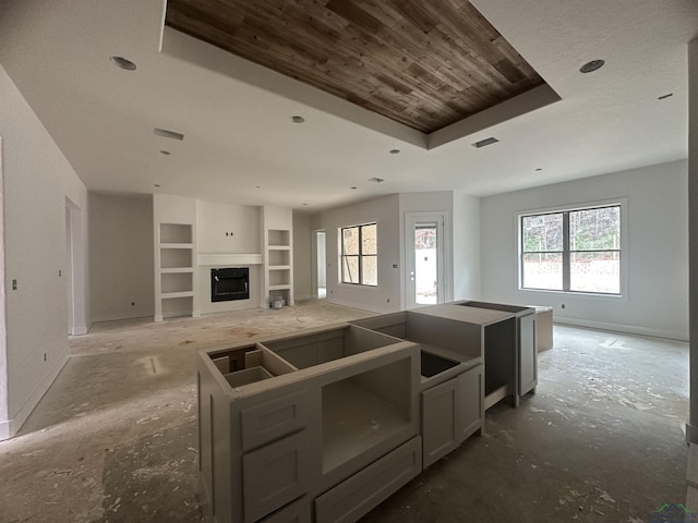 kitchen featuring a kitchen island, a tray ceiling, built in features, and gray cabinetry