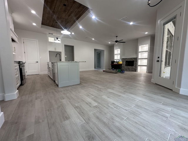 kitchen featuring range with electric stovetop, light wood-style floors, open floor plan, white cabinets, and decorative light fixtures