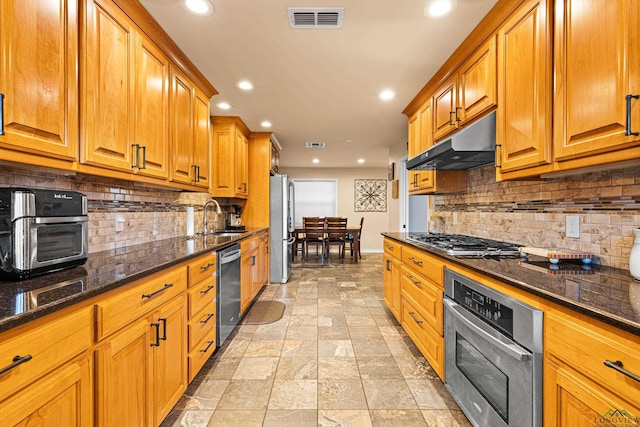 kitchen featuring tasteful backsplash, sink, dark stone counters, and appliances with stainless steel finishes