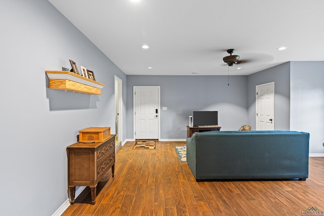 living room featuring ceiling fan and dark hardwood / wood-style floors