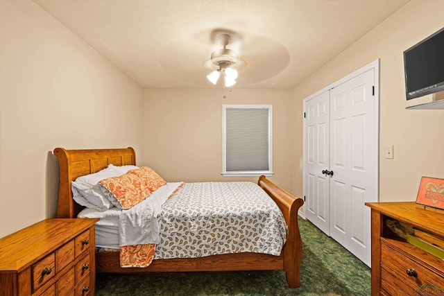 bedroom with ceiling fan, dark carpet, and a closet