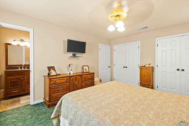 carpeted bedroom featuring connected bathroom, ceiling fan, and multiple closets