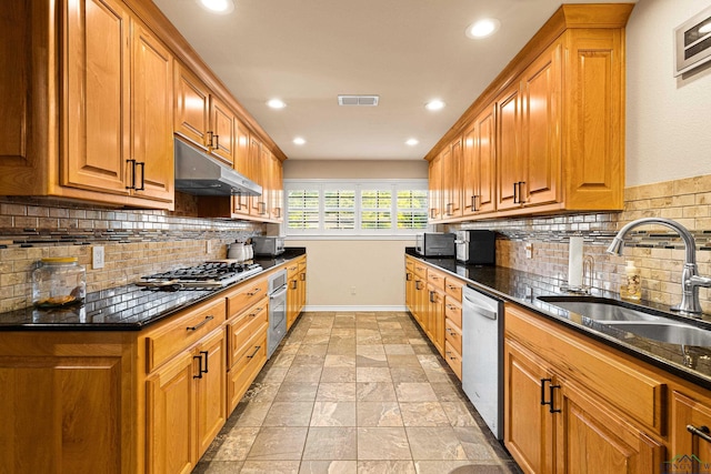 kitchen with stainless steel appliances, tasteful backsplash, dark stone counters, and sink