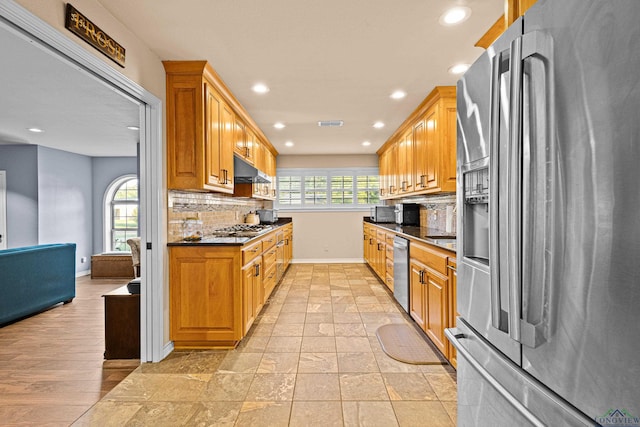 kitchen featuring a wealth of natural light, decorative backsplash, and appliances with stainless steel finishes