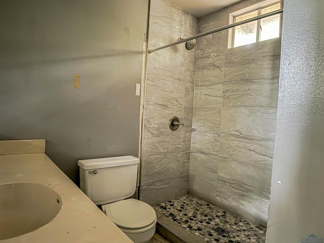 bathroom featuring a tile shower, sink, and toilet