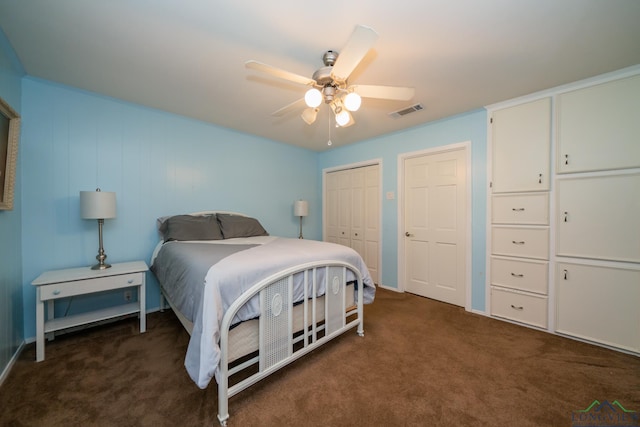 bedroom featuring ceiling fan, dark carpet, and multiple closets