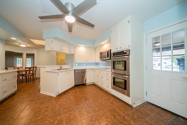 kitchen featuring kitchen peninsula, tasteful backsplash, stainless steel appliances, sink, and white cabinetry