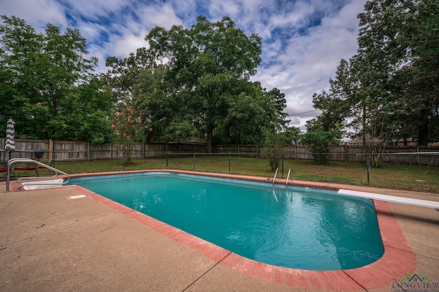 view of swimming pool featuring a yard, a diving board, and a patio area